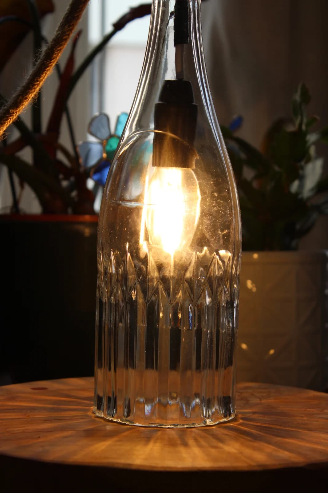 Lampe en verre transparent éteinte avec détails des reliefs géométriques et douille sombre.