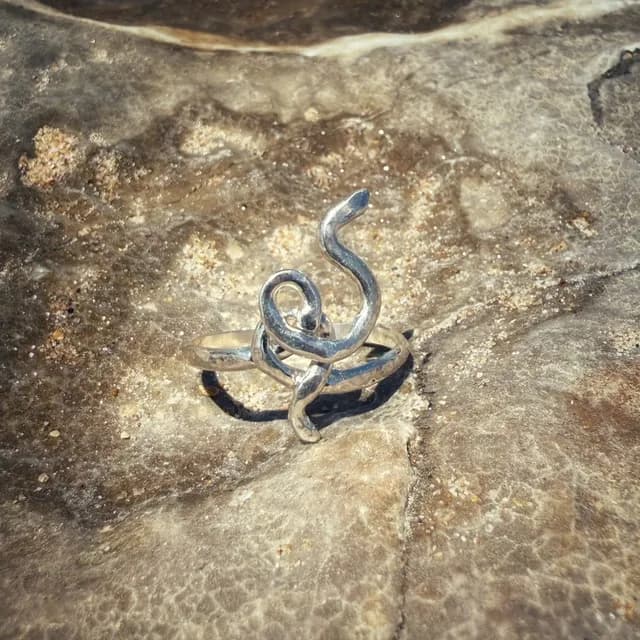 Bague ondulée en argent 925 posée sur une roche texturée.