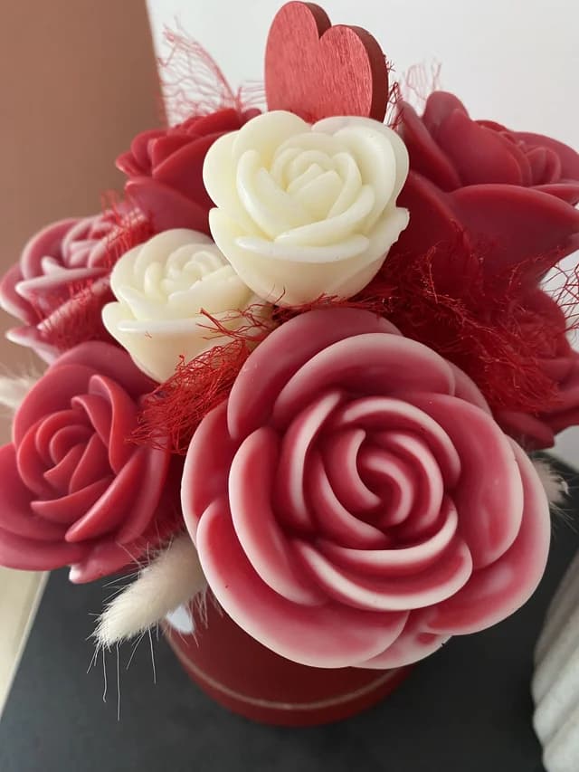 Gros plan sur les roses sculptées rouges et blanches avec détails végétaux et cœur rouge.